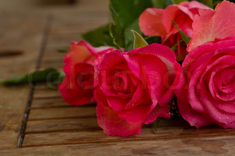 3243170-bouquet-of-pink-roses-in-water-droplets-on-wooden-table